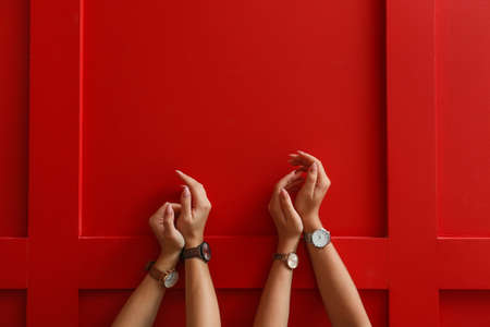 Female hands with stylish watches on color backgroundの写真素材