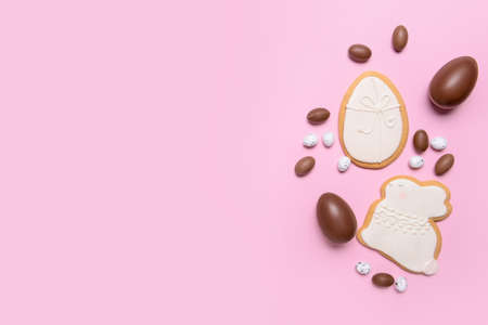 Tasty chocolate eggs and Easter cookies on color background