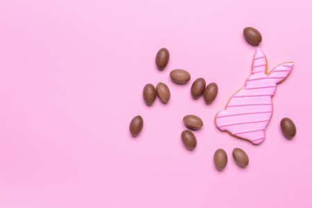 Tasty chocolate eggs and Easter cookie on color backgroundの写真素材