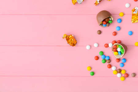 Tasty chocolate egg and candies on color wooden background