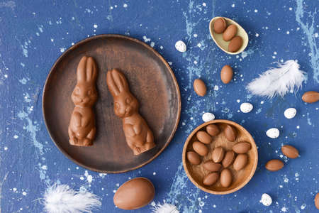 Tasty chocolate Easter bunnies and eggs on color background