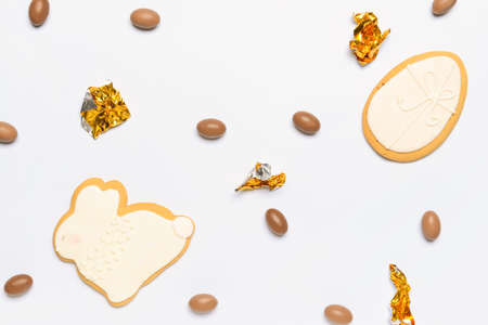 Tasty chocolate candies and Easter cookies on white background