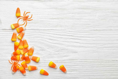 Halloween composition with tasty candy corns on white wooden background