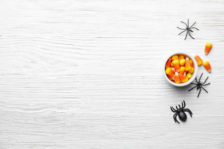Bowl with with tasty candy corns for Halloween on wooden background