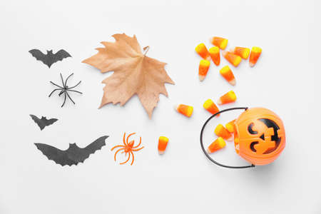Halloween composition with tasty candy corns on white background