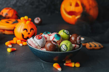 Bowl with tasty treats for Halloween on dark backgroundの写真素材