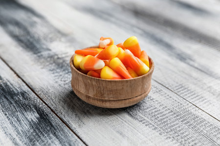 Bowl with with tasty candy corns for Halloween on wooden backgroundの写真素材