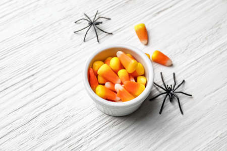 Bowl with with tasty candy corns for Halloween on wooden backgroundの写真素材