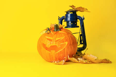 Carved Halloween pumpkin and lantern on color backgroundの写真素材
