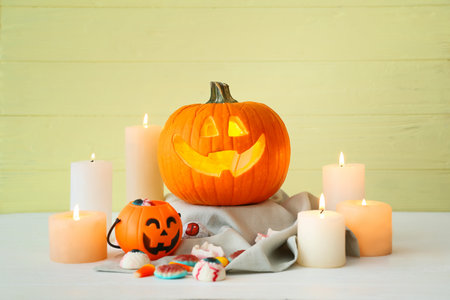 Carved Halloween pumpkin, sweets and candles on table