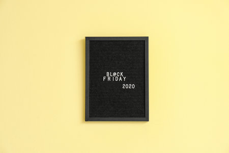 Board with text BLACK FRIDAY on color background