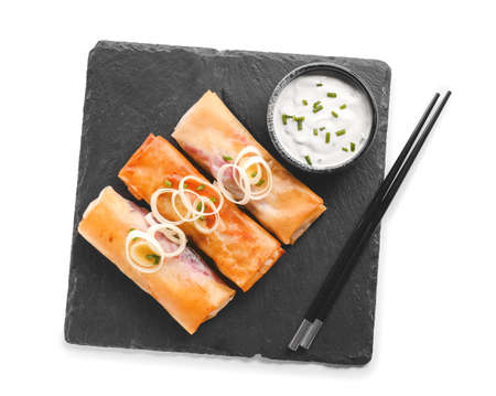 Slate plate with tasty fried spring rolls and sauce on white background