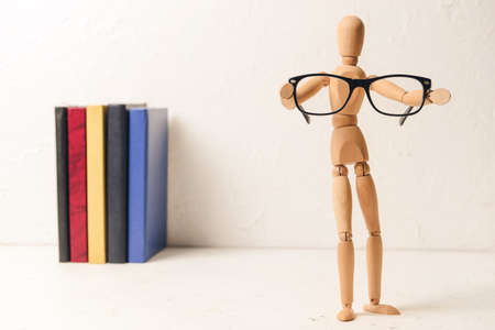 Wooden mannequin with glasses and books on light backgroundの写真素材