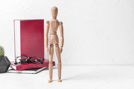 Wooden mannequin with books and glasses on light backgroundの写真素材