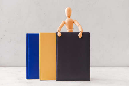 Wooden mannequin with books on light backgroundの写真素材