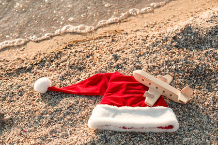 Santa hat and toy airplane on sea beach. Christmas vacation conceptの写真素材