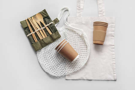 Eco tableware and bags on light background