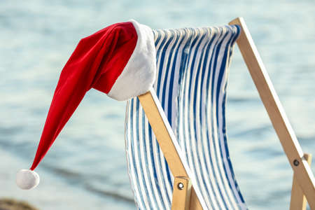 Sun lounger with Santa hat on sea beach. Christmas vacation conceptの写真素材