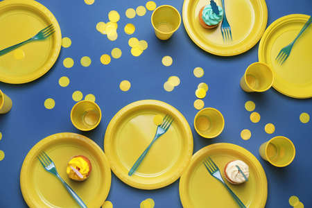 Plastic tableware and confetti on color backgroundの写真素材