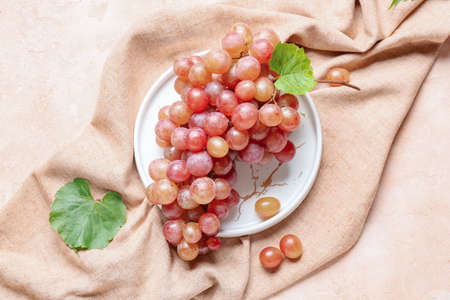 Plate with sweet ripe grapes on color backgroundの写真素材