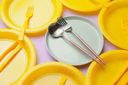 Plastic and ceramic tableware on color backgroundの写真素材