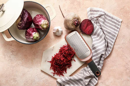 Board with grated beetroot and grater on color backgroundの写真素材