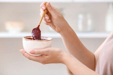 Woman with bowl of delicious homemade plum jam at homeの写真素材