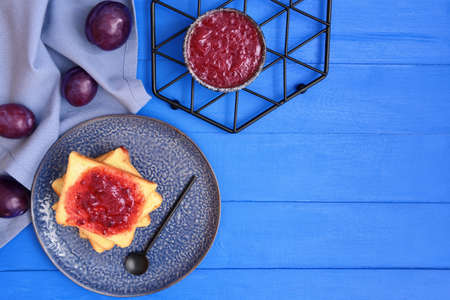 Composition with delicious homemade plum jam on wooden background