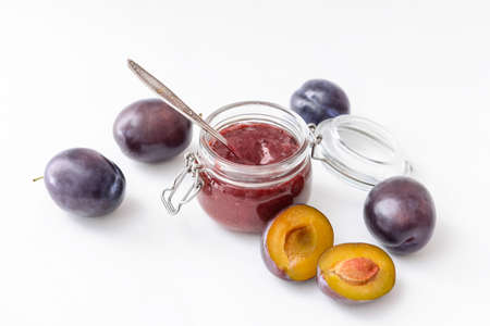 Glass jar with delicious homemade plum jam on white backgroundの写真素材