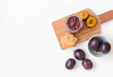 Glass jar with delicious homemade plum jam on white backgroundの写真素材