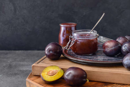 Composition with delicious homemade plum jam on dark background