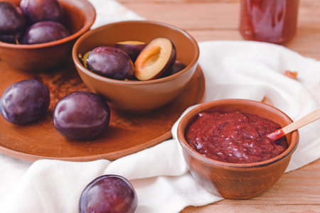 Bowl with delicious homemade plum jam on wooden backgroundの写真素材