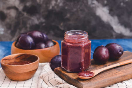 Glass jar with delicious homemade plum jam on color backgroundの写真素材