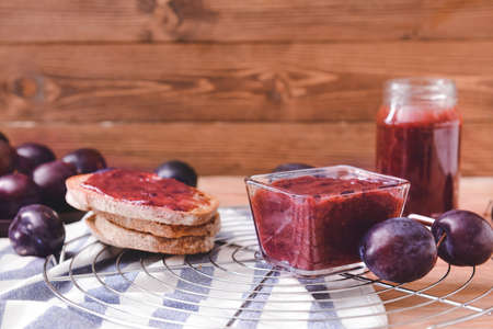 Composition with delicious homemade plum jam on wooden background