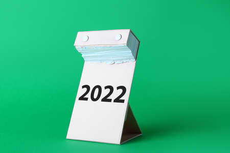 Tear-off calendar at the end of the year with 2022 on color background. Concept of new years goalsの写真素材