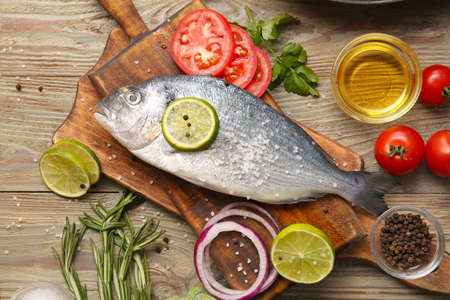 Raw dorado fish with ingredients on wooden background