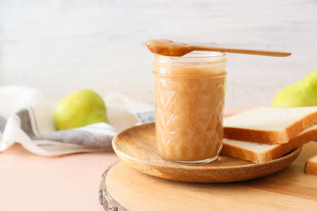 Jar of tasty pear jam with bread on wooden tableの写真素材