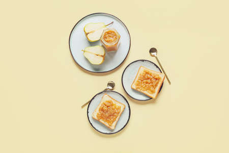 Jar of tasty pear jam with bread on color backgroundの写真素材