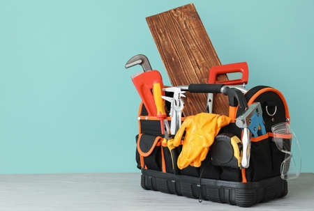 Set of construction tools on wooden table against color background
