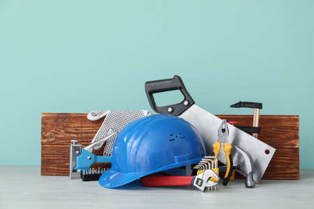 Set of construction tools on wooden table against color background
