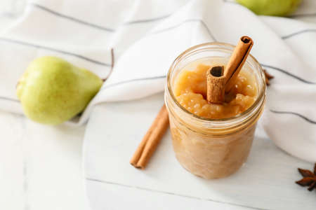 Jar of tasty pear jam on table