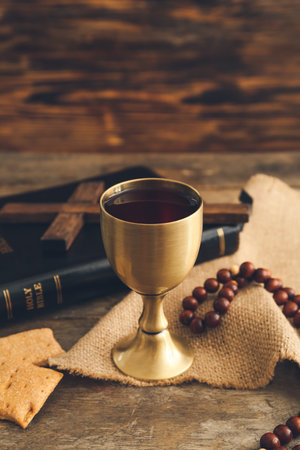 Chalice of wine with bread, beads and Holy Bible on wooden backgroundの写真素材