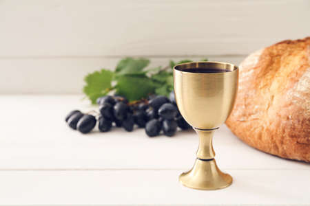 Chalice of wine with bread on white wooden backgroundの写真素材
