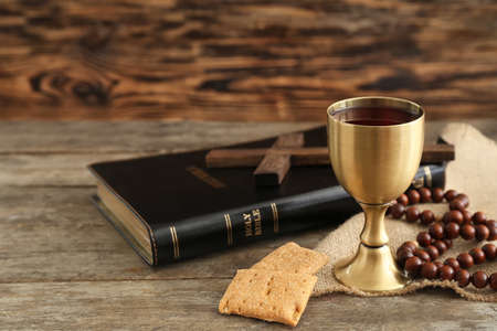Chalice of wine with bread, beads, cross and Holy Bible on wooden backgroundの写真素材