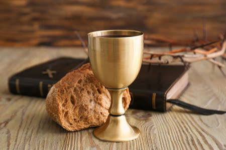 Holy Bible with bread and chalice of wine on wooden backgroundの写真素材