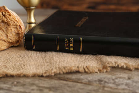 Holy Bible with bread on wooden table