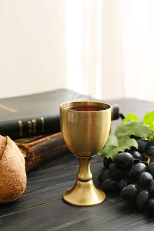 Chalice of wine with bread and Holy Bible on tableの写真素材