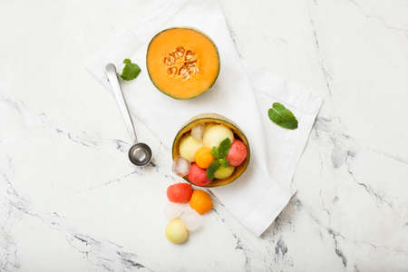 Tasty melon balls with ice on white background
