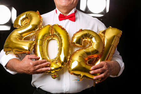 Elderly man with figure 2021 on dark background. New Year celebrationの写真素材