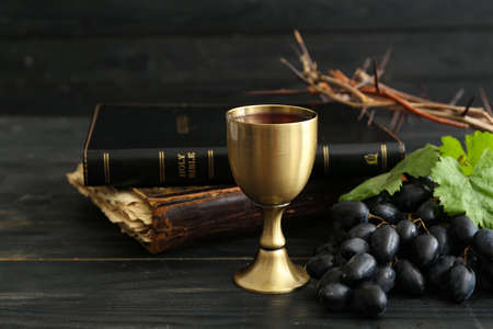 Chalice of wine with Holy Bible and crown of thorns on dark wooden backgroundの写真素材